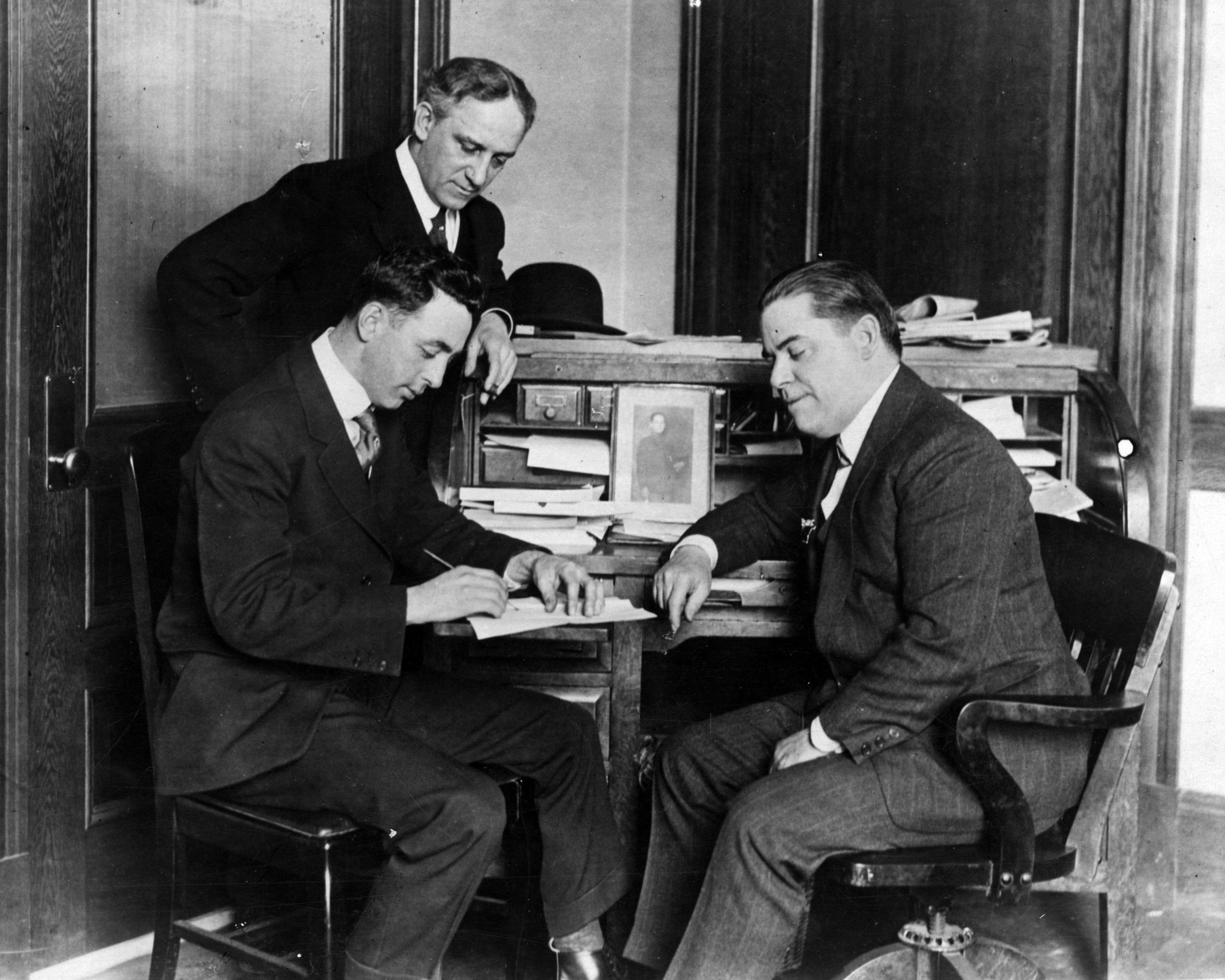Red Sox player-manager, left, signs his 1917 contract as owner Frazee looks on.